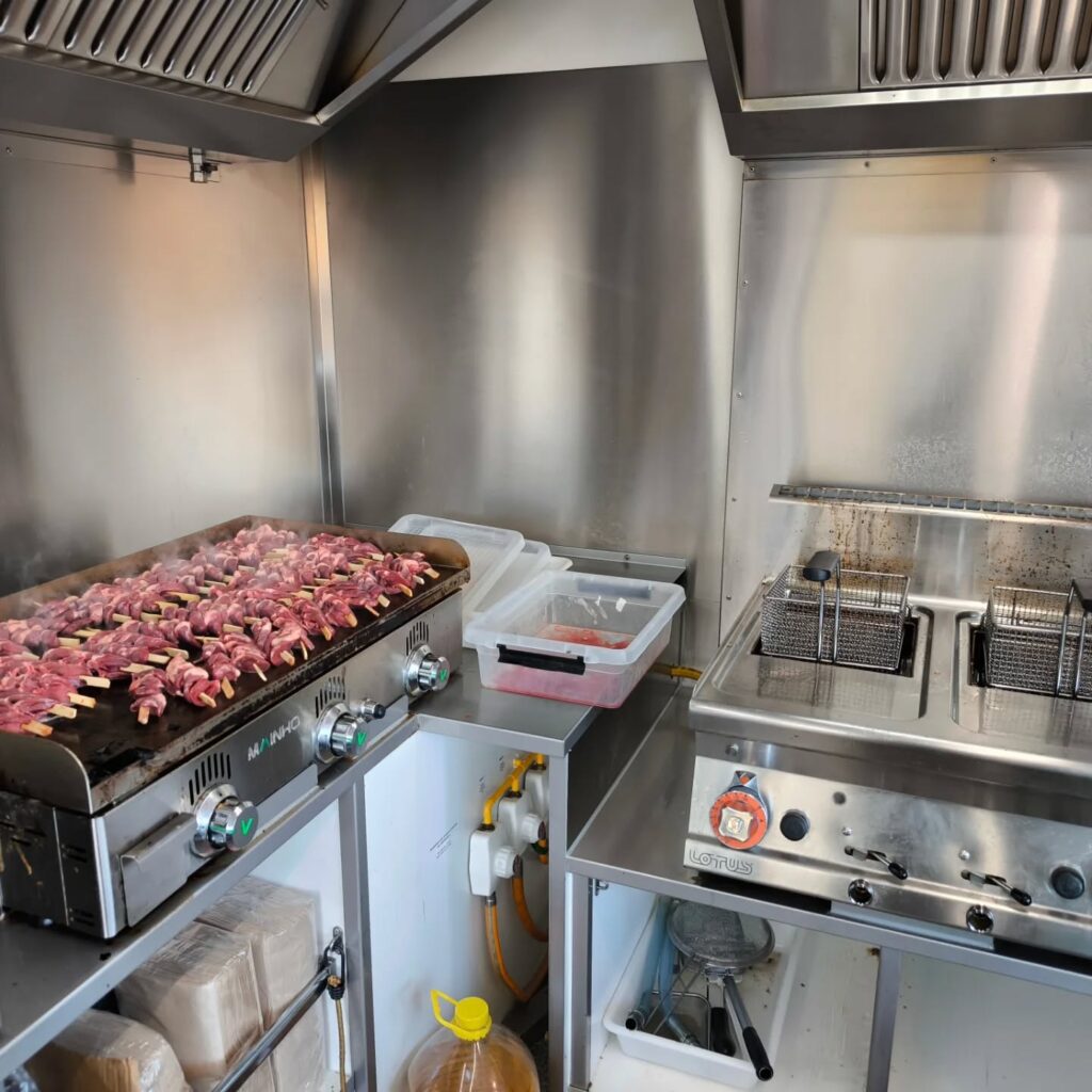 Cuisine professionnelle avec brochettes de viande crues sur plaque chauffante MAÍNH O et friteuse double LOTUS en inox.