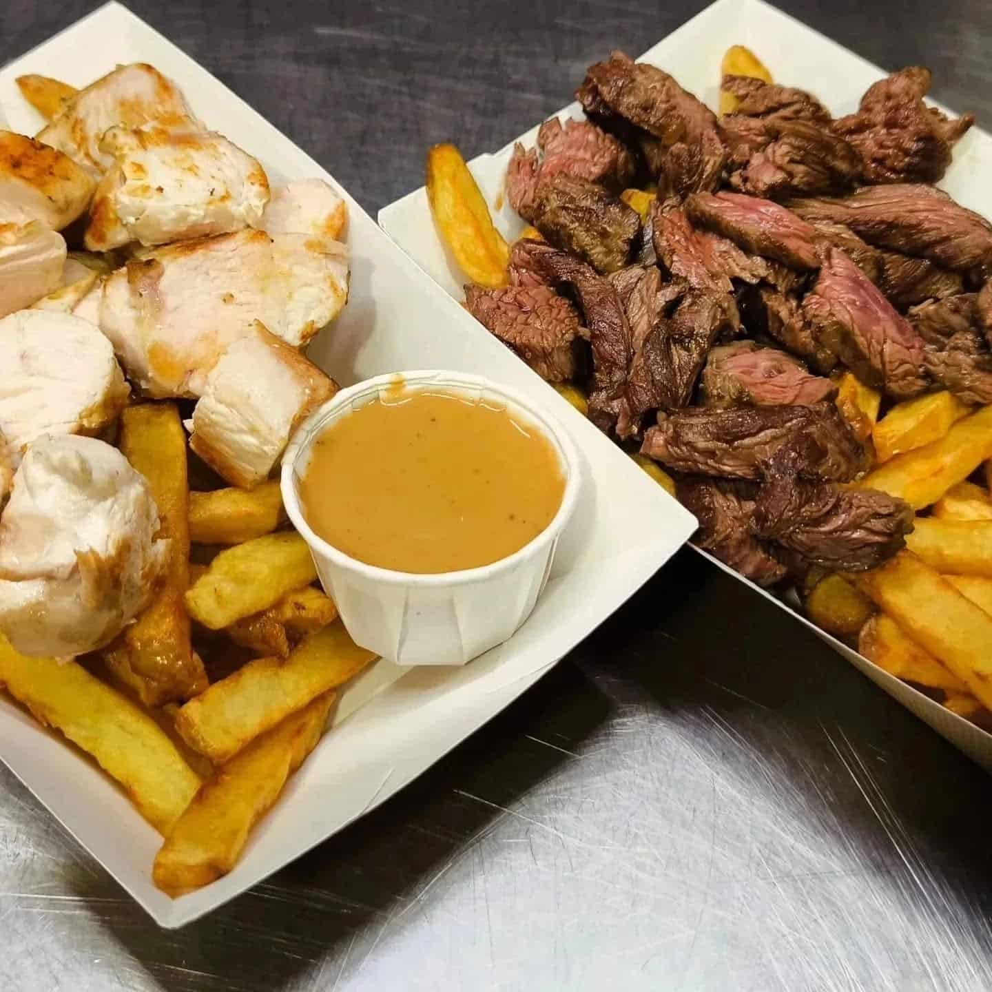 Deux barquettes de plats à emporter : poulet grillé et frites avec sauce d'un côté, et steak coupé en lanières et frites de l'autre.
